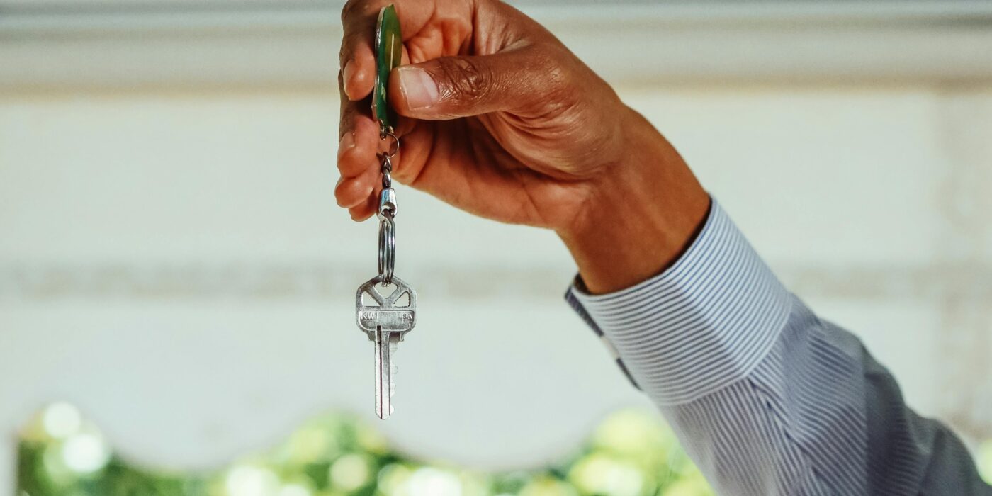 A property owner hands over a set of keys to a professional property manager, signifying a strategic partnership built on trust and expertise.