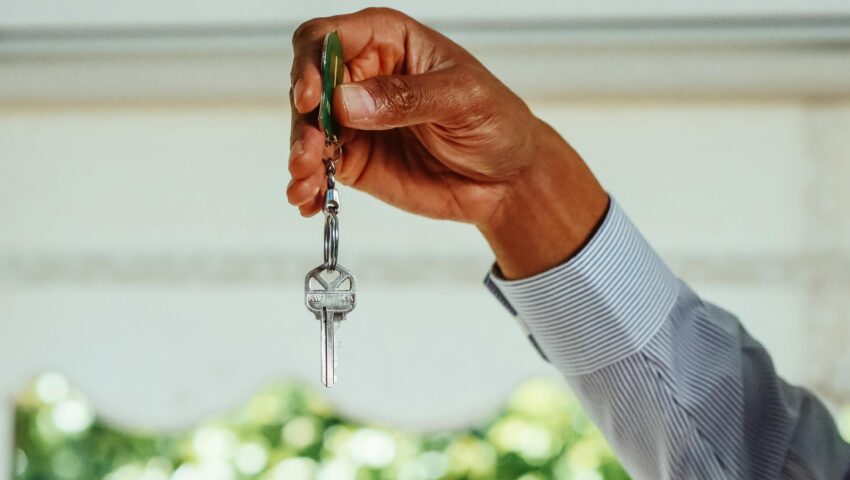 A property owner hands over a set of keys to a professional property manager, signifying a strategic partnership built on trust and expertise.